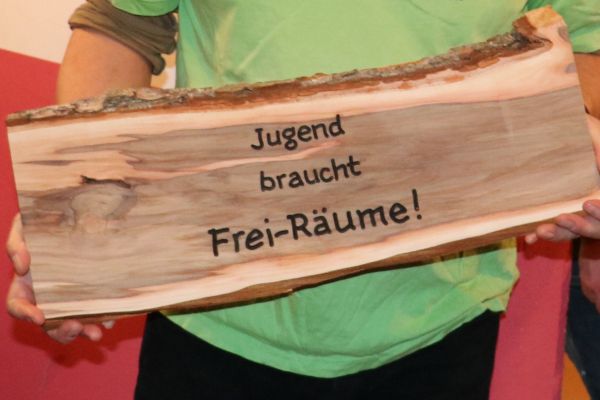 Holzschild mit Beschriftung "Jugend braucht Räume"